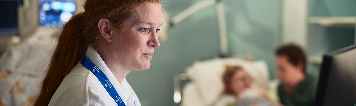 En sjuksköterska i förgrunden med en familj i bakgrunden